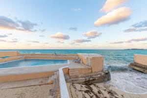 a swimming pool on the beach next to the ocean at Harbour Mews - Oceanfront Townhouse in Nassau