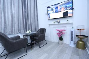 倫敦的住宿－London Town Apartment- Lewisham，客厅配有两把椅子和电视