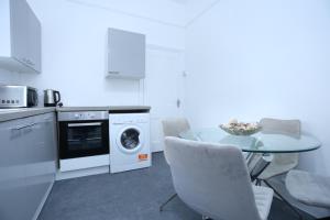 a kitchen with a table and chairs and a dishwasher at London Town Apartment- Lewisham in London