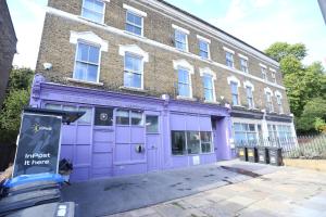 倫敦的住宿－London Town Apartment- Lewisham，砖楼前的紫色商店