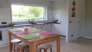 a kitchen with a wooden table with chairs and a window at Villa 't Zonneroosje in Nieuwpoort +28 photos