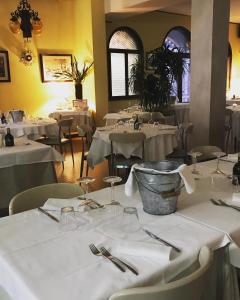 una sala da pranzo con tavoli e sedie bianchi e argenteria di Hotel Ristorante Gallo D'Oro a Vignola