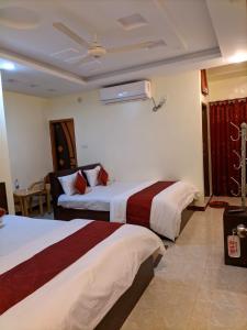 um quarto de hotel com duas camas e um sofá em Elite Cox's Resort em Cox's Bazar