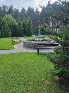 a park with two benches and a fountain at Dworek za Lasem in Warta