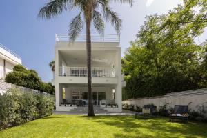 a white house with palm trees in the yard at Cube 67 - Villa in Palermo