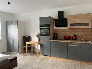 a kitchen with gray cabinets and a table with a table at Bei der Kahnfährfrau Mit NEUEM Innenhof Garten in Lübben