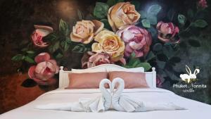 a bedroom with a bed with a painting of roses at Phuket Nonnita Boutique Resort & Organic Farm in Phuket