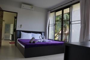 a bedroom with a bed with purple sheets and windows at Twin Villas Apartment with Swimming Pool in Wok Tum