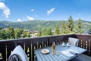 a table on a balcony with a view of mountains at Résidence Pierre & Vacances Premium Les Fermes De Méribel in Méribel