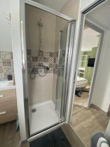 a shower with a glass door in a bathroom at Côté Village By Mel & Jérôme 