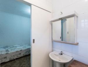 a bathroom with a sink and a mirror and a bed at Apt no Menino Deus in Porto Alegre