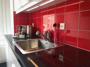 a kitchen with a sink in a red tiled wall at Grubenmann Appartements - Sankt Gallen City in St. Gallen