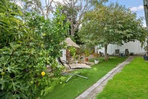 a garden with a bench and trees and grass at Charming House; Walk to Beach & Shops in Rosebud