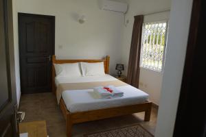 a bedroom with a bed with white sheets and a window at Zeph self catering in Baie Lazare Mahé