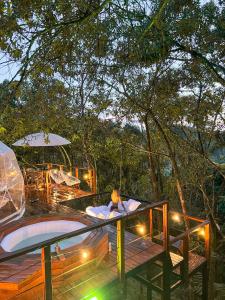 una terraza con bañera de hidromasaje y un patio con mesa. en Solana Glamping, en Pereira