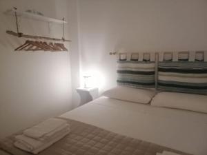 una camera da letto bianca con un letto e asciugamani di Oblò sul Mare - Villa nel cuore del Salento a Lendinuso