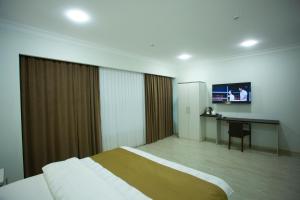 a bedroom with a bed and a desk and a monitor at Viva Hotel in Tashkent