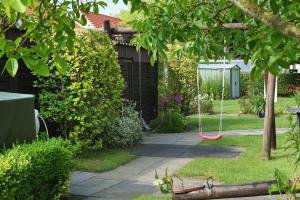 a garden with a red swing in the yard at Ferienwohnungen Haus Saathoff in Bensersiel
