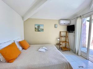 een slaapkamer met een bed met oranje kussens en een raam bij Résidence Storia di Blue in Porto-Vecchio