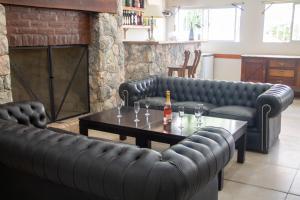 sala de estar con sofás de cuero negro y mesa en Apart Hotel Savona en Capilla del Monte