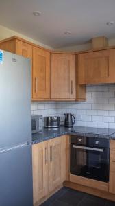 uma cozinha com armários de madeira e um frigorífico em Lovely 3-bedroom apartment in Colchester em Colchester