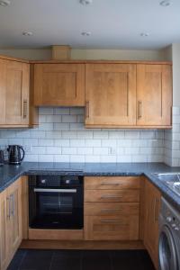 コルチェスターにあるLovely 3-bedroom apartment in Colchesterのキッチン(木製キャビネット、黒い食器洗い機付)