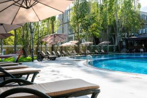 ein Pool mit Stühlen und Sonnenschirmen neben einem Gebäude in der Unterkunft VOGUE HOTEL RESORT AND SPA - Nabran in Nabran