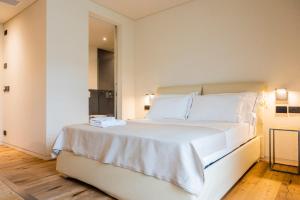 um quarto branco com uma cama grande e lençóis brancos em Bihotel em Comerzo