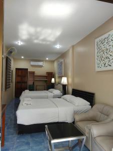 a hotel room with four beds and a couch at NB House in Karon Beach