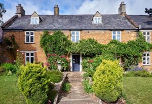 uma velha casa de tijolos com uma porta azul em Easington Guest House em Banbury