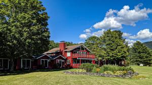 a large red house on a field with trees at North Shire Lodge in Manchester