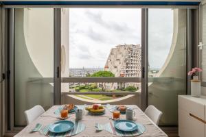 a dining room with a table with food and a large window at Au Paradis bleu - Parking privé - Literie confortable - Vue port - Plage à 5 min in La Grande-Motte +17 photos