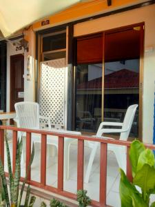 a porch with white chairs and glass doors at NB House in Karon Beach