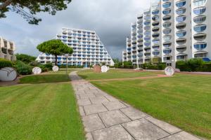 a park in front of two tall buildings at Au Paradis bleu - Parking privé - Literie confortable - Vue port - Plage à 5 min in La Grande-Motte