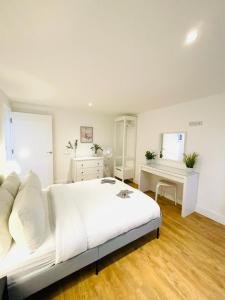 a white bedroom with a large bed and a desk at Prosper House Apartments in Norwich
