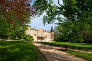 a driveway leading to a large building with a church at Château de Champ-Renard in Blacé