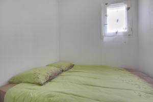 a bed with a green comforter and a window at Le Loriot in Saint-Nic