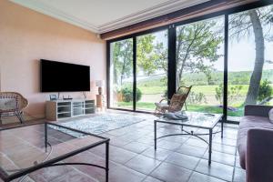 ein Wohnzimmer mit einem TV und großen Fenstern in der Unterkunft Villa DaoL - Villa avec piscine et jacuzzi in Flassans-sur-Issole