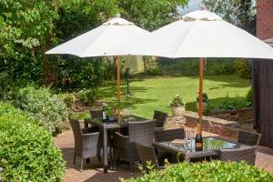 einen Tisch und Stühle unter einem Sonnenschirm in einem Garten in der Unterkunft Easington Guest House in Banbury