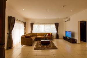 - un salon avec un canapé et une télévision dans l'établissement Accra Fine Suites - Holi Flats Airport Residential, à Accra