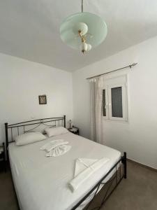 een slaapkamer met een groot wit bed en een kroonluchter bij GIANNIS-KLEOPATRA HOUSE 1 in Kerames