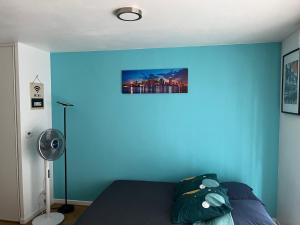 - une chambre avec un mur bleu et un lit dans l'établissement Superbe studio lumineux haut de gamme tout confort, à Drancy