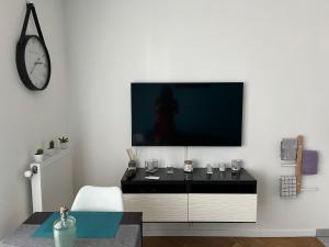 sala de estar con TV en una pared blanca en Superbe studio lumineux haut de gamme tout confort en Drancy