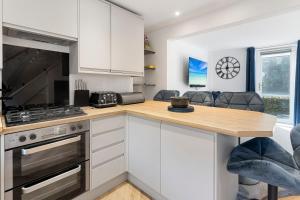 eine Küche mit weißen Schränken und einer Holzarbeitsplatte in der Unterkunft River Exe Cottage waterfront in Exeter