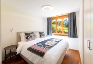 a bedroom with a white bed with a window at Panoramapark Soleil B Garden Apartment in Wengen
