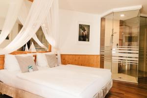 a bedroom with a white bed and a glass shower at Das Stadthaus in Neusiedl am See