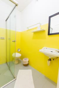 a yellow bathroom with a sink and a toilet at Hotel Blumenau Centro in Curitiba