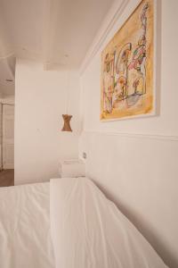 a white bedroom with a painting on the wall at Hostal Copart in San Pedro de Atacama