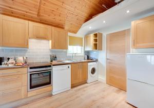 a kitchen with wooden cabinets and a white refrigerator at Garden Lodge in Worlingworth