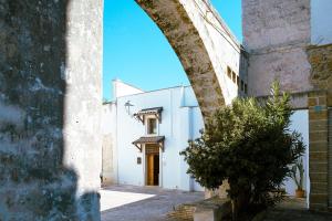 ein Torbogen, der zu einem weißen Gebäude mit einer Tür führt in der Unterkunft B&B Casa Maddalena in Campi Salentina